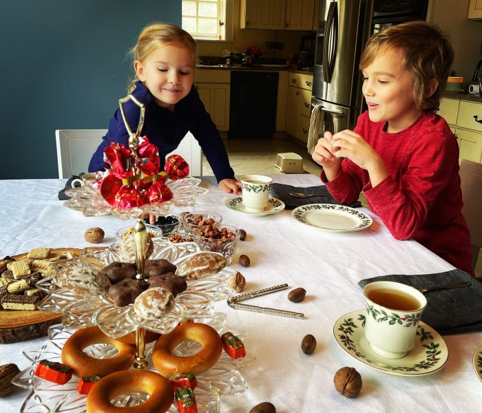 2 young kids at the table of sweets and tea