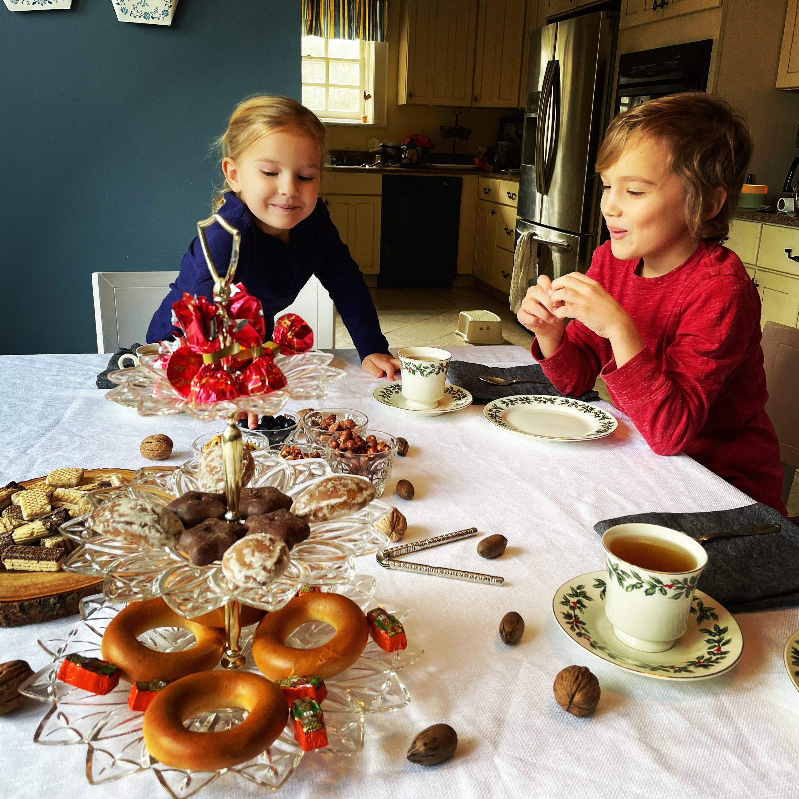2 young kids at the table of sweets and tea